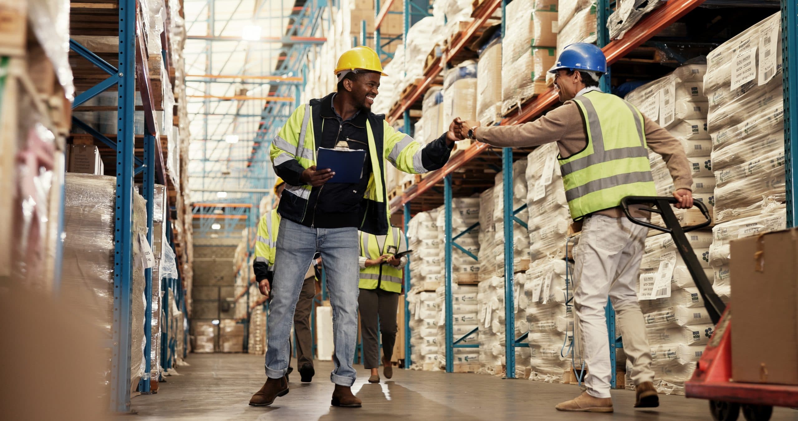 men-fist-bump-teamwork-warehouse-logistics-clipboard-greeting-by-shelf-respect-inspection-people-happy-inventory-distribution-smile-supply-chain-industrial-plant